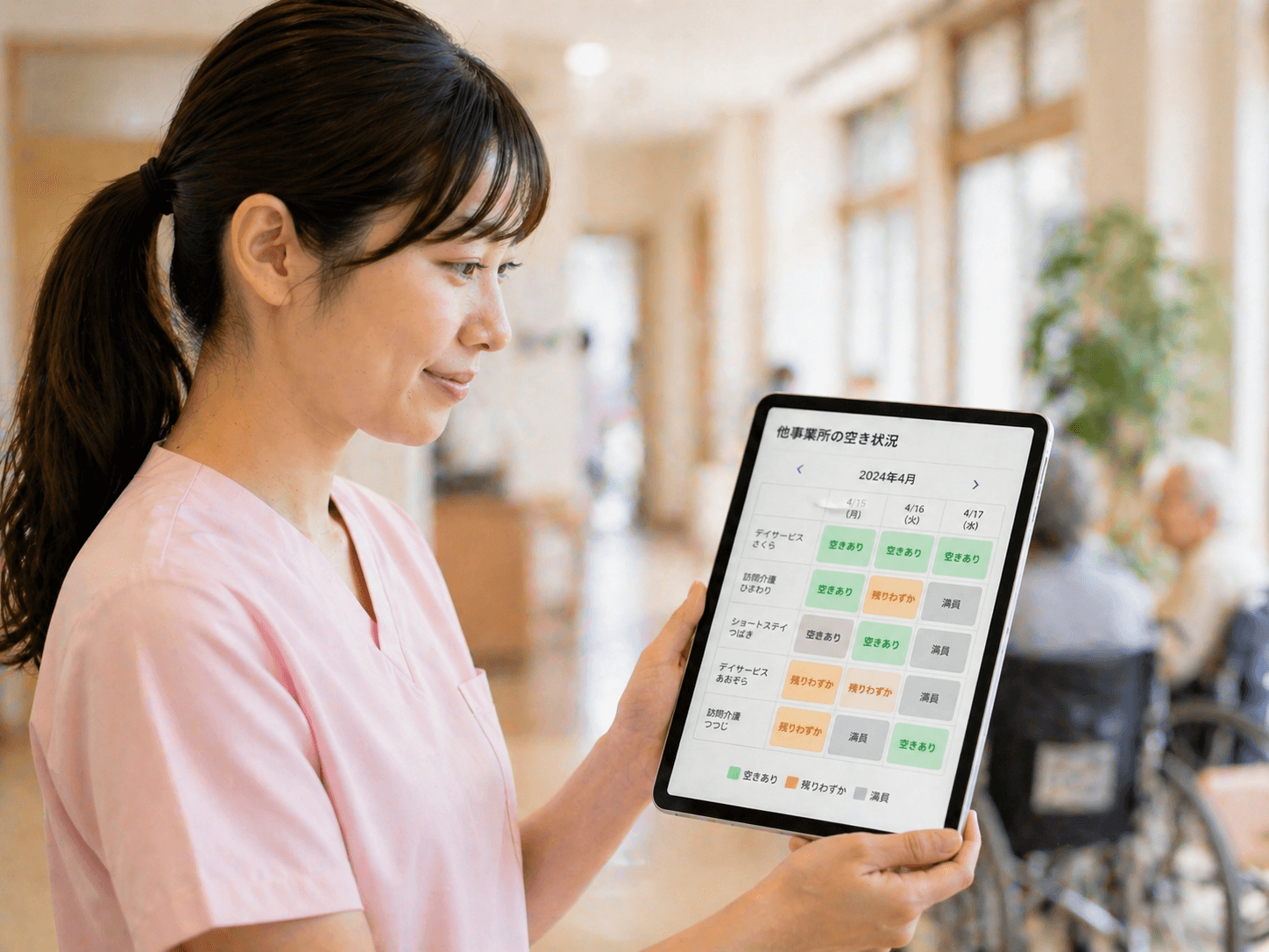 タブレットで他事業所の空き状況カレンダーを確認するスタッフ