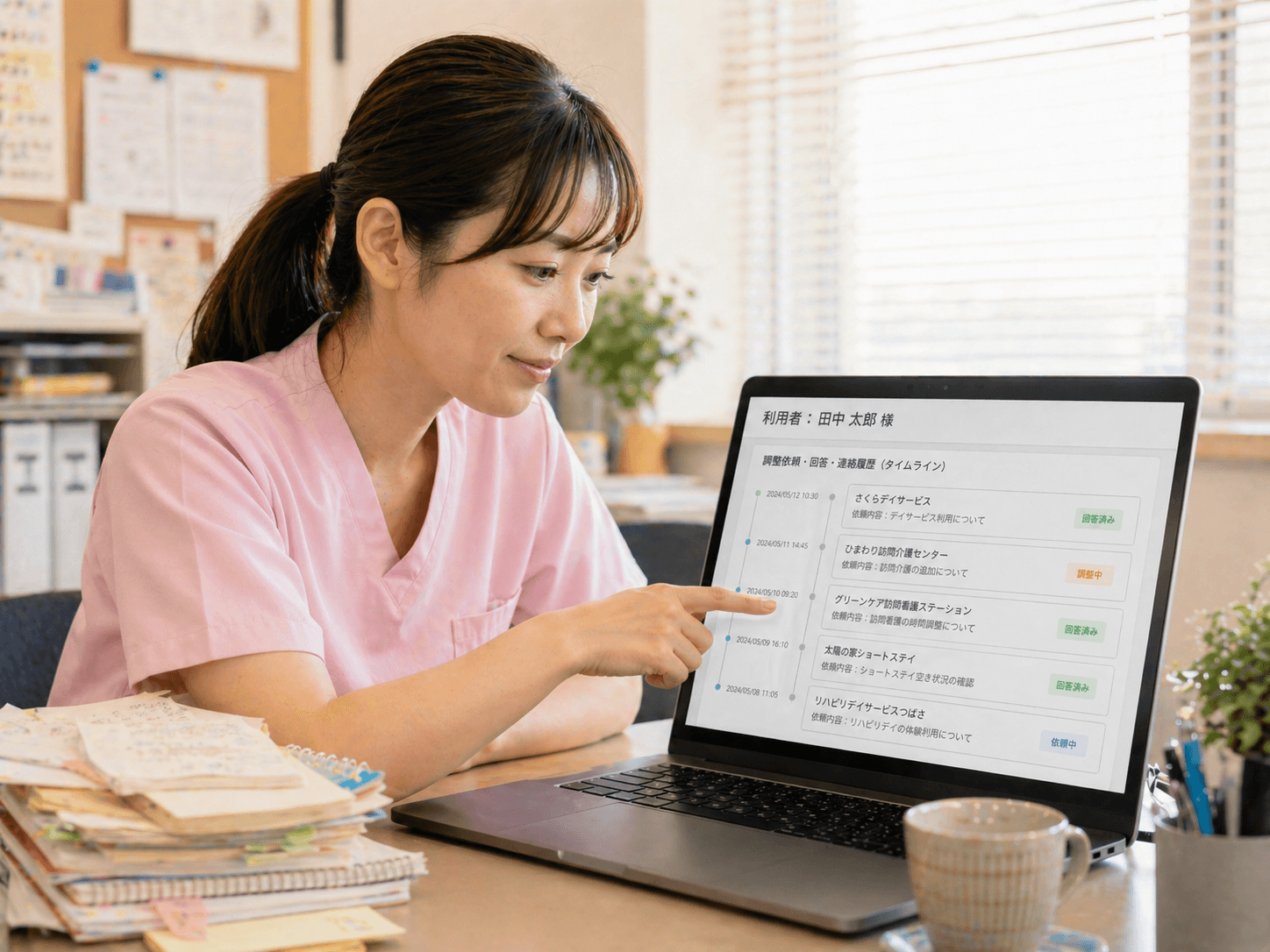 ノートPCで利用者単位の調整タイムラインを指差して確認するスタッフ